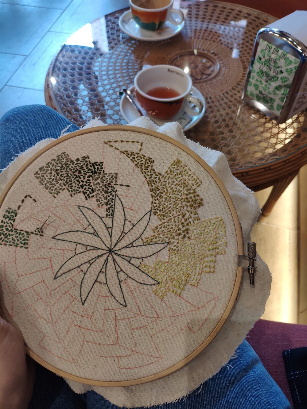 Mesa de la cafetería con un té, mientras una clienta borda