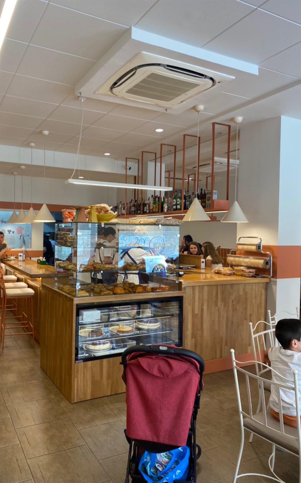 Interior de La Despensa de Tani: barra de madera, vitrina de tartas y lámparas cónicas