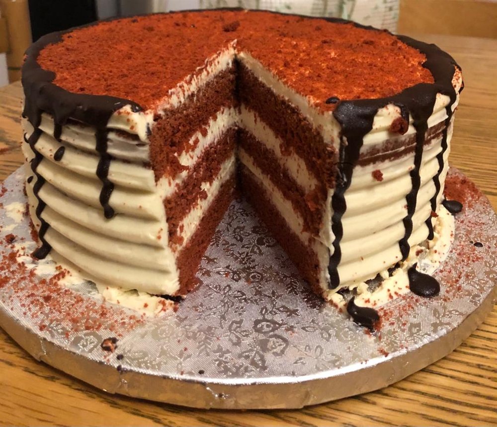 Tarta red velvet entera, cortada, con crema y chocolate